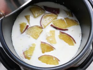 電気圧力鍋の内釜に牛乳を注ぎ、煮込みの準備をしている様子