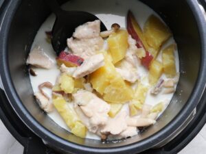 鶏むね肉とさつまいもをお玉でやさしくかき混ぜている様子
