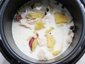 鶏むね肉・さつまいも・玉ねぎ・しめじが入った白いスープを煮込んでいる様子