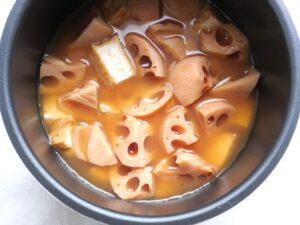 煮上がった厚揚げとれんこんのあら熱を取り、味をしみ込ませている様子