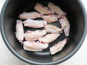 電気圧力鍋の釜底に鶏手羽中を並べ入れた状態