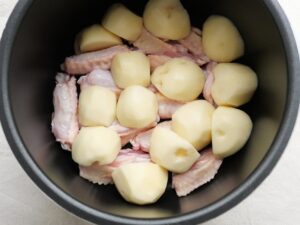 電気圧力鍋に鶏手羽中とじゃがいもを重ねて入れた調理前の状態