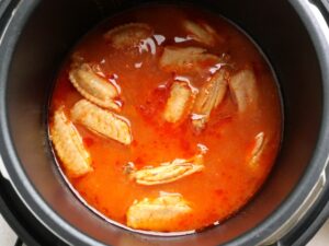 電気圧力鍋でケチャップベースの煮汁を煮詰め、鶏手羽中に味をしみ込ませている様子