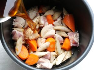 電気圧力鍋の内釜にだし汁・醤油・砂糖・みりんの煮汁を注いでいるところ