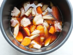 電気圧力鍋の内釜に煮汁を注ぎ終わったところ。鶏もも肉・ごぼう・人参が煮汁に浸った状態
