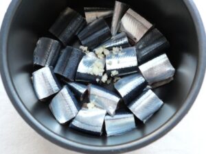 電気圧力鍋の内釜のさんまの上に、にんにくのすりおろしを加えたところ