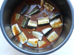 煮汁を入れ終わった電気圧力鍋の内釜。さんまが煮汁に浸った状態