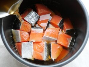 電気圧力鍋の内釜に、だし汁・醤油を混ぜた煮汁を注ぎ入れている様子