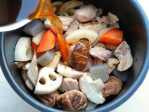 電気圧力鍋の内釜にだし汁・醤油・砂糖・みりんの煮汁を注いでいるところ