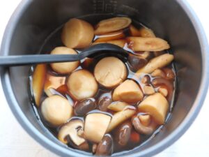 内釜の具材を混ぜ合わせて煮汁に浸し、あら熱を取る工程