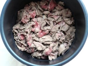 電気圧力鍋の内釜に玉ねぎと牛肉を重ね入れた状態