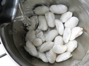 水戻し中の白花豆が入ったボウルに、お湯を注いでいる様子