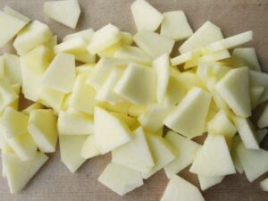 5mm厚のいちょう切りのりんごをまな板の上に重ねた様子。ジャム作りの下ごしらえ工程