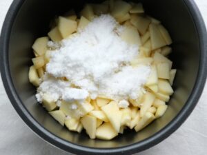 いちょう切りのりんごの上に、半量の砂糖を入れた状態