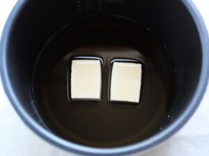 電気圧力鍋の釜に木綿豆腐と煮汁を入れた様子