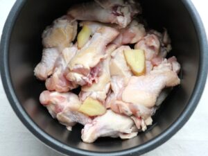 鶏手羽元の上に、生姜の薄切りをのせたところ