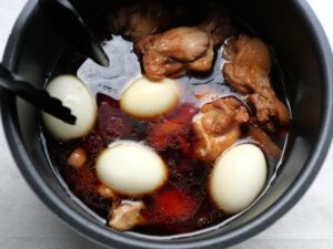 煮汁にゆで卵を入れ、浸かるように位置を整えている様子