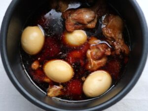 煮込み後に、内釜で煮汁に浸かったゆで卵と鶏手羽元。あら熱取り工程