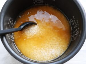 だし汁と調味料と米をシリコンスプーンでかき混ぜている様子
