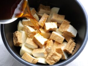 厚揚げとじゃがいもの上から煮汁を注いでいる様子