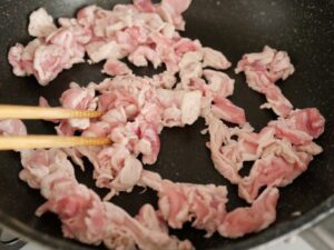 ごま油を熱したフライパンで豚肉を炒めているところ