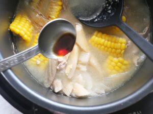 内釜に大さじで醤油を加えているところ