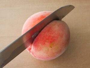 桃のコンポートの下準備。種に沿って包丁で切り込みを入れている様子