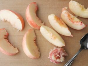 皮付きのままくし切りにした桃と、取り除いた種
