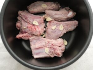内釜に豚スペアリブ、にんにくの薄切りを入れたところ