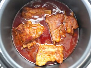 煮込み中の豚スペアリブ。茶色のもったりとした煮汁の中で煮えている