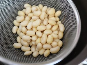 ざるに上げた大豆。ゆでこぼしが2回終わった状態