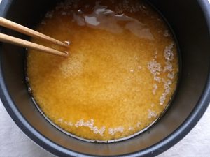 米をかき混ぜ、水と醤油、砂糖を混ぜ合わせている様子