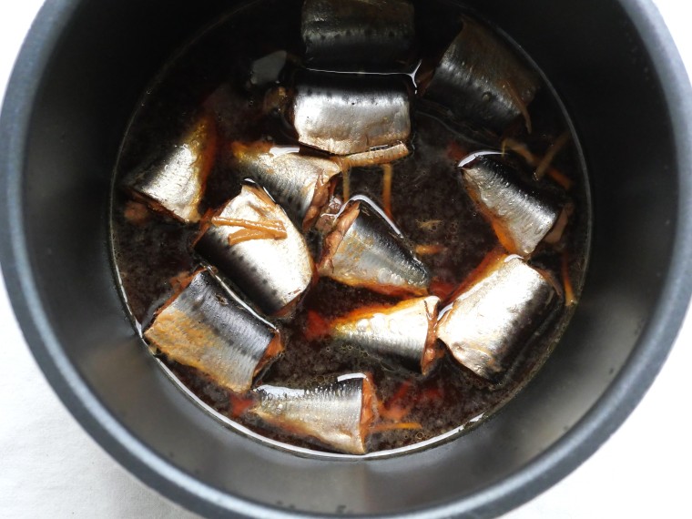 電気圧力鍋で煮込んだ、いわしのさっぱり煮。黒っぽい煮汁に浸っている